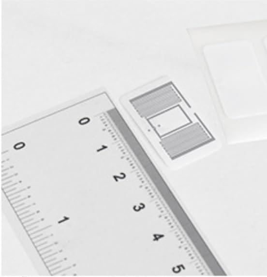 A 27 by 15 millimetre UHF RFID label lying next to a ruler for scale